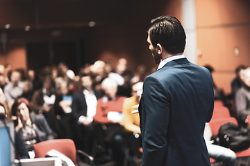 Image showing Speaker giving a talk on corporate Business Conference. Audience at the conference hall. Business and Entrepreneurship event