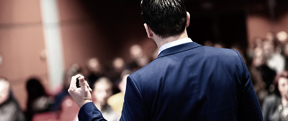 Image showing Rear view of speaker giving a talk on corporate Business Conference. Audience at the conference hall. Business and Entrepreneurship event. Panoramic composition