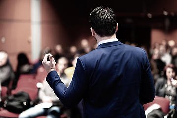 Image showing Rear view of speaker giving a talk on corporate Business Conference. Audience at the conference hall. Business and Entrepreneurship event. Panoramic composition