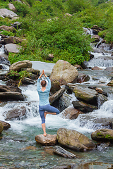 Image showing Woman in yoga asana Vrikshasana tree pose at waterfall outdoors