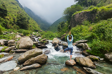 Image showing Woman in yoga asana Vrikshasana tree pose at waterfall outdoors