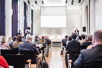 Image showing Speaker giving a talk in conference hall at business event. Rear view of unrecognizable people in audience at the conference hall. Business and entrepreneurship concept.