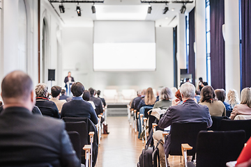 Image showing Speaker giving a talk in conference hall at business event. Rear view of unrecognizable people in audience at the conference hall. Business and entrepreneurship concept.