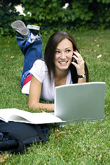 Image showing Cute teen girl laying down on the grass studying