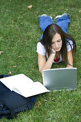 Image showing Cute teen girl laying down on the grass studying