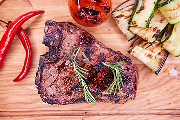 Image showing Grilled T-Bone Steak on serving board on wooden background