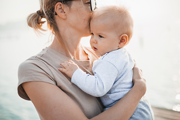 Image showing Tender woman caressing her little baby boy infant child outdoors. Mother's unconditional love for her child