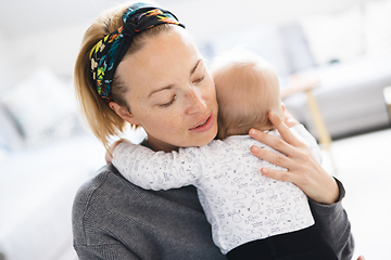 Image showing Tender woman caressing her little baby boy infant child at home. Mother's unconditional love for her child