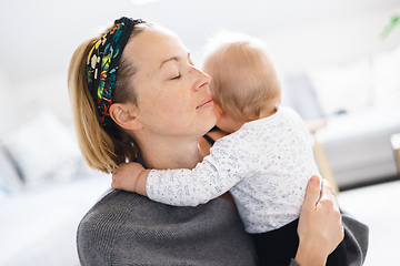 Image showing Tender woman caressing her little baby boy infant child at home. Mother's unconditional love for her child