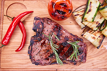 Image showing Grilled T-Bone Steak on serving board on wooden background