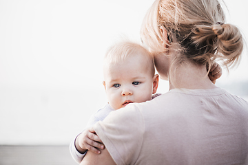 Image showing Tender woman caressing her little baby boy infant child outdoors. Mother's unconditional love for her child