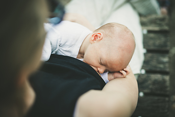 Image showing Mother breast feeding and hugging her baby boy outdoors.