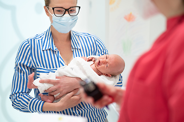 Image showing Mother holding her baby boy at medical appointment at pediatrician office.