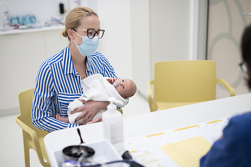 Image showing Mother holding her baby boy at medical appointment at pediatrician office.