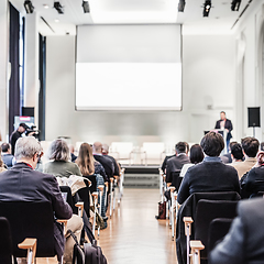 Image showing Speaker giving a talk in conference hall at business event. Rear view of unrecognizable people in audience at the conference hall. Business and entrepreneurship concept.