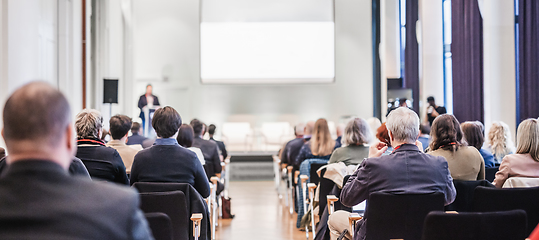 Image showing Speaker giving a talk in conference hall at business event. Rear view of unrecognizable people in audience at the conference hall. Business and entrepreneurship concept.