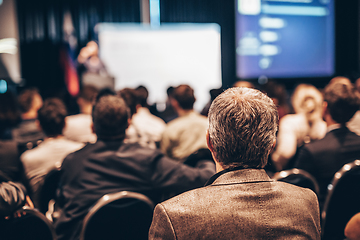 Image showing Speaker giving a talk in conference hall at business event. Rear view of unrecognizable people in audience at the conference hall. Business and entrepreneurship concept.