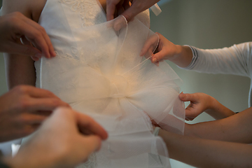 Image showing Hands of girlfriends helping the bride to dress her dress