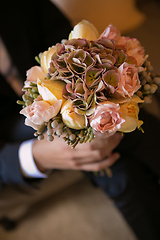 Image showing Groom holding in hands delicate, expensive, trendy bridal wedding bouquet of flowers
