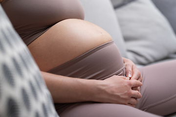 Image showing Pregnant woman belly. Pregnancy Concept. Pregnant tummy close up. Detail of pregnant woman relaxing on comfortable sofa at home.