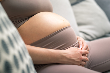 Image showing Pregnant woman belly. Pregnancy Concept. Pregnant tummy close up. Detail of pregnant woman relaxing on comfortable sofa at home.