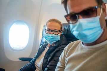 Image showing A young couple wearing face masks while traveling on airplane. New normal travel after covid-19 pandemic concept