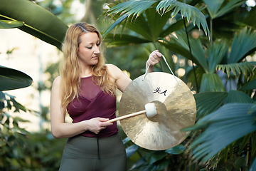 Image showing Yoga concept, meditation and sound therapy. Beautiful young caucasian woman performing tibetan gong music therapy.