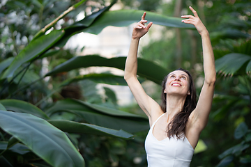 Image showing Female meditating and practicing yoga in tropical rainforest. Beautiful young woman practicing yoga outdoor with tropical forest in background.