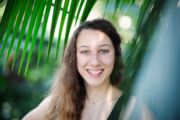 Image showing Young beautiful natural cheerful woman with healthy face and skin in exotic greenery. Closeup fresh face of attractive girl. Summer model. Natural beauty concept