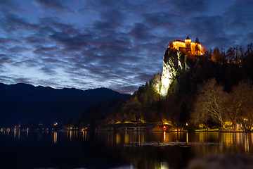 Image showing Dramatic cloudscape over medieval castle of Bled perched on cliff above Bled lake at dusk, Slovenia.