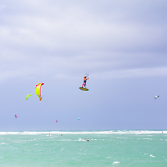 Image showing Kiteboarding. Fun in the ocean. Extreme Sport Kitesurfing. Kitesurfer jumping high in the air performing triks during kitesurfing session.