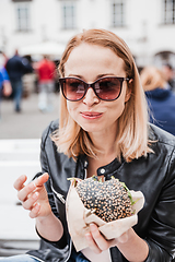 Image showing Pretty young blonde funny woman eating hamburger outdoor on the street