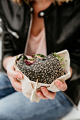 Image showing Close up of woman hands holding delicious organic salmon vegetarian burger on open air beer an burger urban street food festival in Ljubljana, Slovenia.