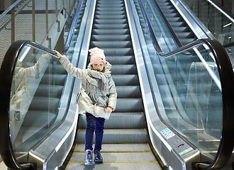 Image showing From below shot of girl standing on moving stairs in terminal.