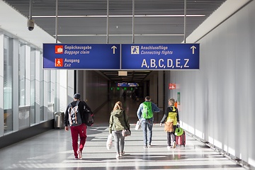 Image showing Unrecognizable People With Bags And Suitcase Walking In Airport Terminal. Rear View Of Passengers On Their Way To Flight Boarding Gate, Ready For Business Travel Or Vacation Journey.