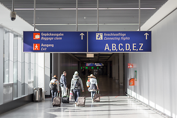 Image showing Unrecognizable People With Bags And Suitcase Walking In Airport Terminal. Rear View Of Passengers On Their Way To Flight Boarding Gate, Ready For Business Travel Or Vacation Journey.