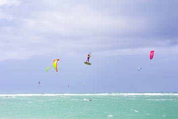 Image showing Kiteboarding. Fun in the ocean. Extreme Sport Kitesurfing. Kitesurfer jumping high in the air performing triks during kitesurfing session.