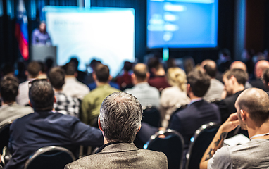 Image showing Speaker giving a talk in conference hall at business event. Rear view of unrecognizable people in audience at the conference hall. Business and entrepreneurship concept.