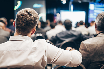 Image showing Speaker giving a talk in conference hall at business event. Rear view of unrecognizable people in audience at the conference hall. Business and entrepreneurship concept.