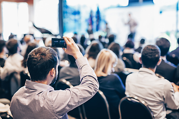 Image showing Speaker giving a talk in conference hall at business event. Rear view of unrecognizable people in audience at the conference hall. Business and entrepreneurship concept.