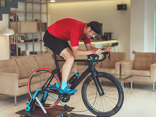 Image showing A man riding a triathlon bike on a machine simulation in a modern living room. Training during pandemic conditions.