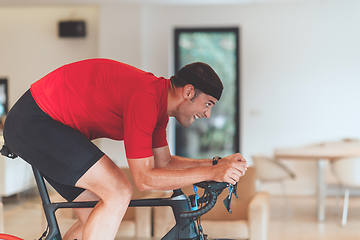 Image showing A man riding a triathlon bike on a machine simulation in a modern living room. Training during pandemic conditions.