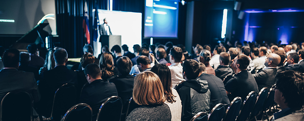 Image showing Speaker giving a talk in conference hall at business event. Rear view of unrecognizable people in audience at the conference hall. Business and entrepreneurship concept.