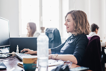 Image showing Yound devoted female software developers team working on desktop computer in IT statup company.