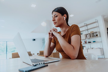 Image showing Woman sitting in living room using laptop look at cam talk by video call with business friend relatives, head shot. Job interview answering questions.