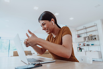 Image showing Woman sitting in living room using laptop look at cam talk by video call with business friend relatives, head shot. Job interview answering questions.