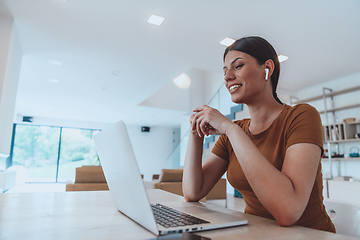 Image showing Woman sitting in living room using laptop look at cam talk by video call with business friend relatives, head shot. Job interview answering questions.