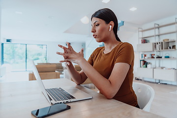 Image showing Woman sitting in living room using laptop look at cam talk by video call with business friend relatives, head shot. Job interview answering questions.