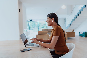 Image showing Woman sitting in living room using laptop look at cam talk by video call with business friend relatives, head shot. Job interview answering questions.