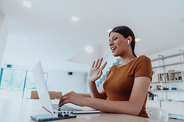 Image showing Woman sitting in living room using laptop look at cam talk by video call with business friend relatives, head shot. Job interview answering questions.